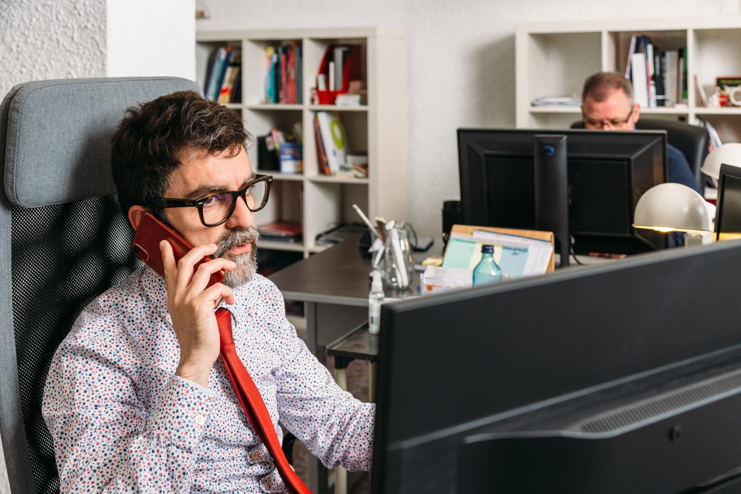 University Phone System | VitalPBX for Higher Ed 2 Staff member on a phone call at an office desk